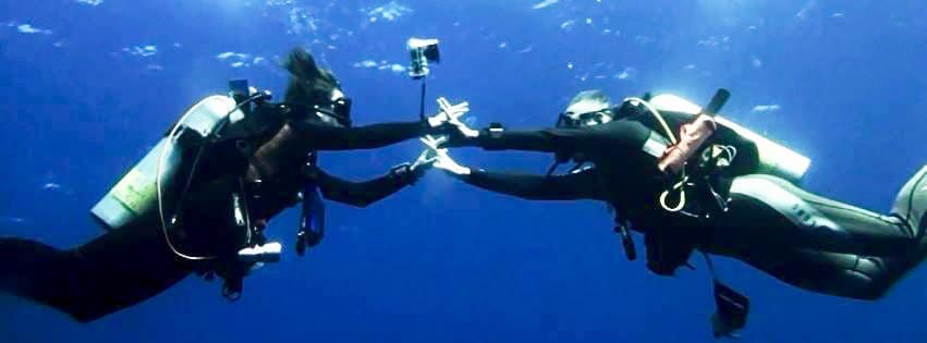 Un couple de plongeurs se donnent la main sous l'eau en étant allé plonger en couple