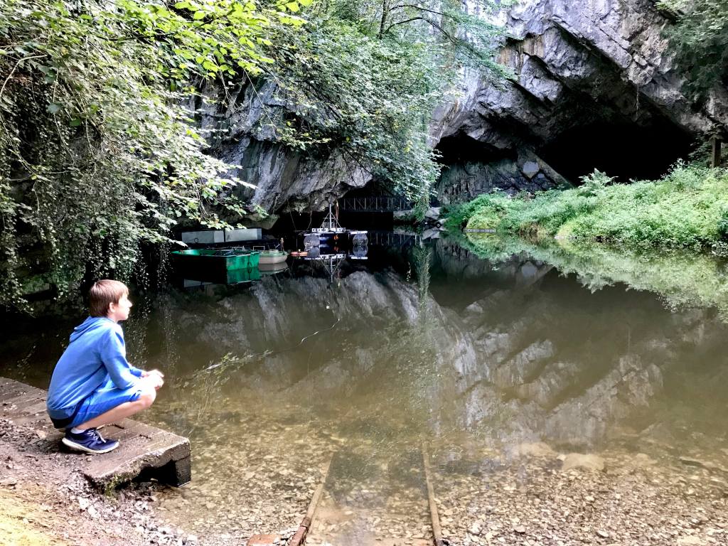 Un enfant regarde un plan d'eau à l'entrée d'une grotte