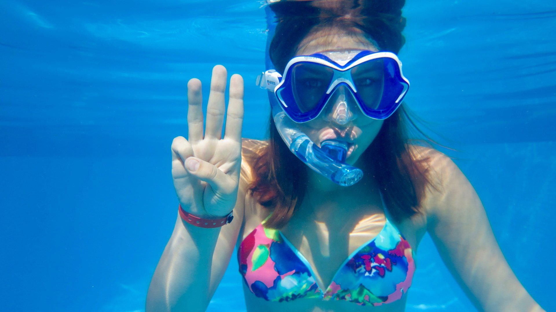 Une jeune fille montre un trois avec ses doigts pour expliquer le briefing de plongée