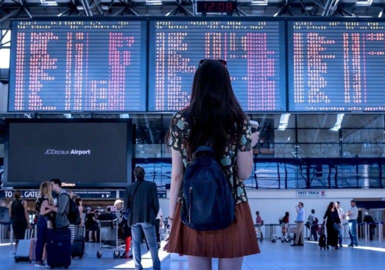 Une femme regarde les tableaux d'arrivées et de départs dans un aéroport