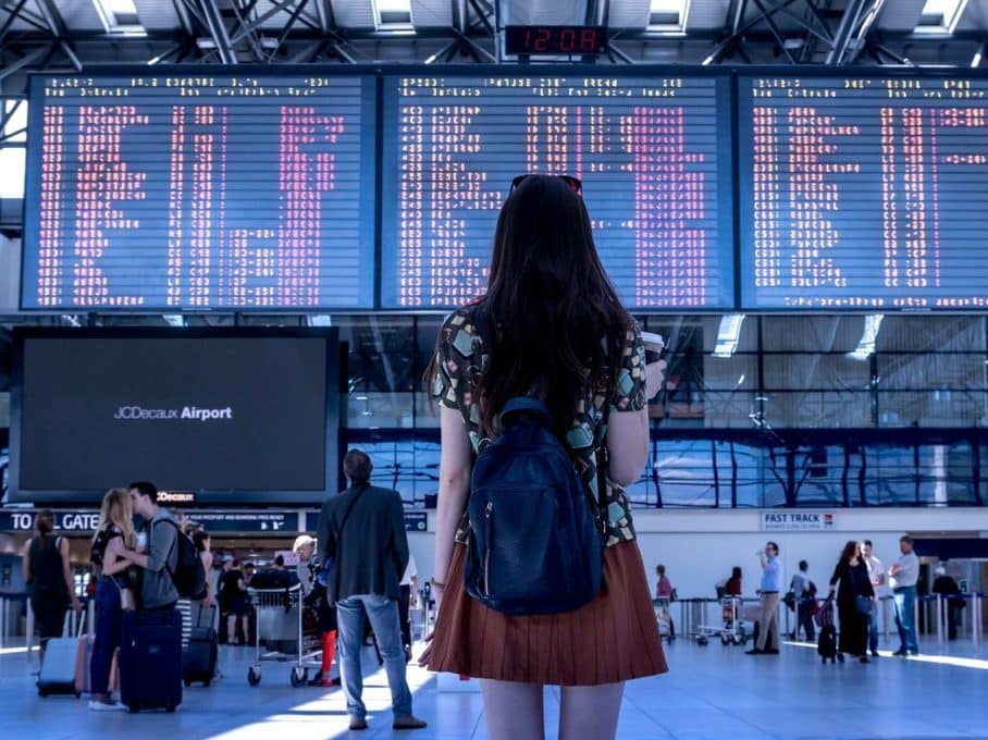 Une femme regarde les tableaux d'arrivées et de départs dans un aéroport