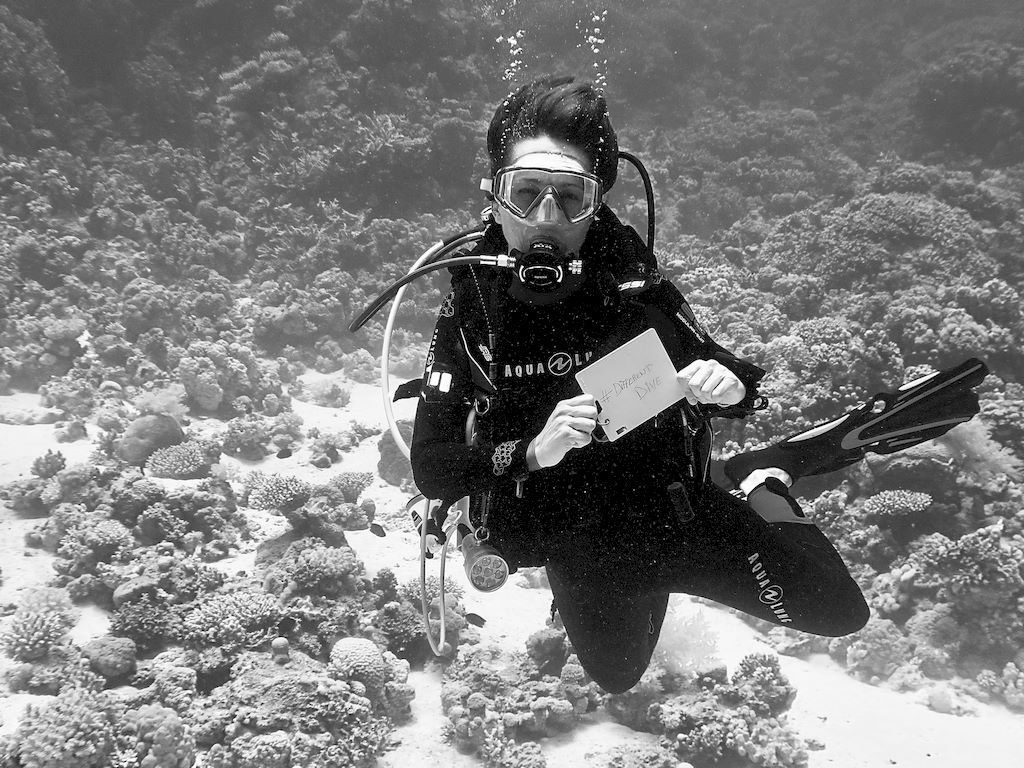 Une plongeuse montre un tableau blanc sous l'eau pour inciter les abonnés à s'inscrire à la newsletter