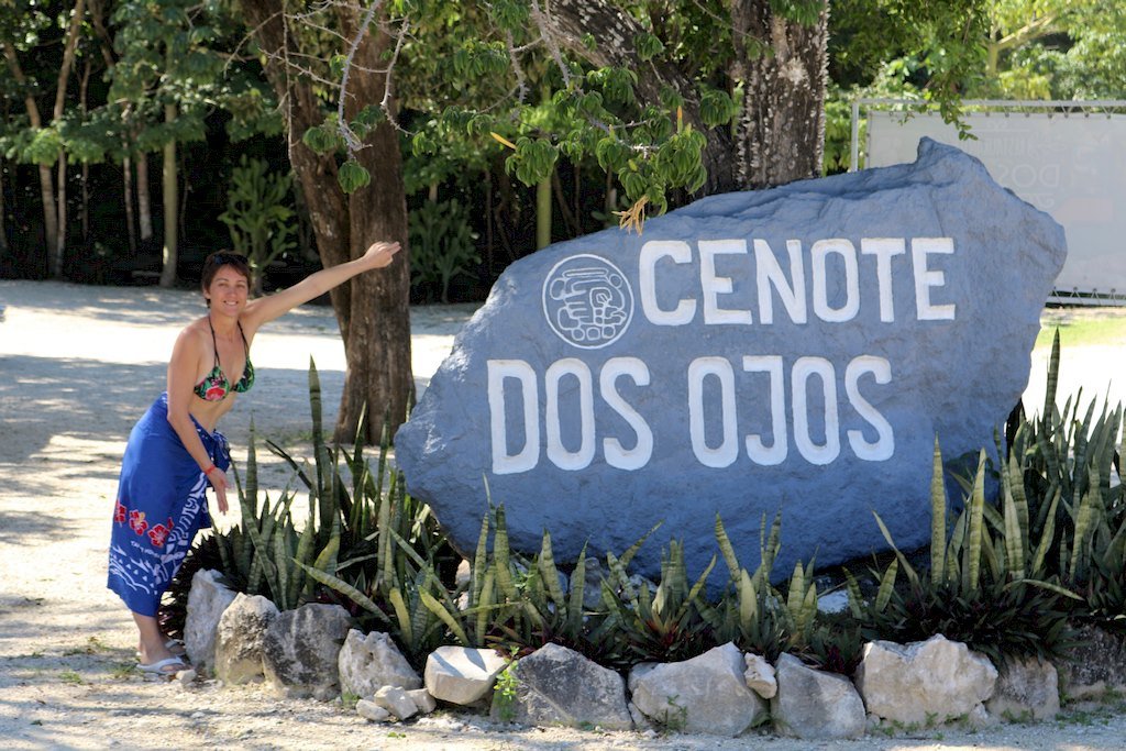 Une femme montre la pierre à l'entrée du site de Dos Ojos