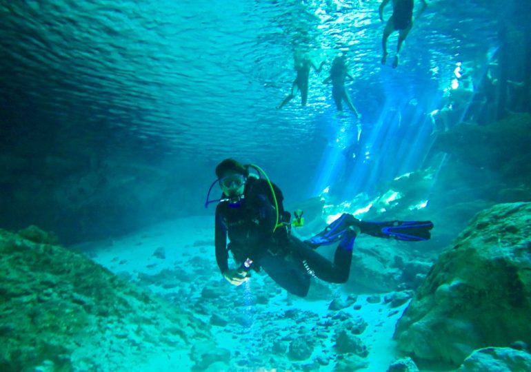 Une plongeuse s'immerge dans le cenote de Dos Ojos