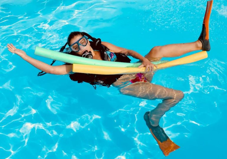 Une femme équipée pour plonger se tient à des boudins de piscine