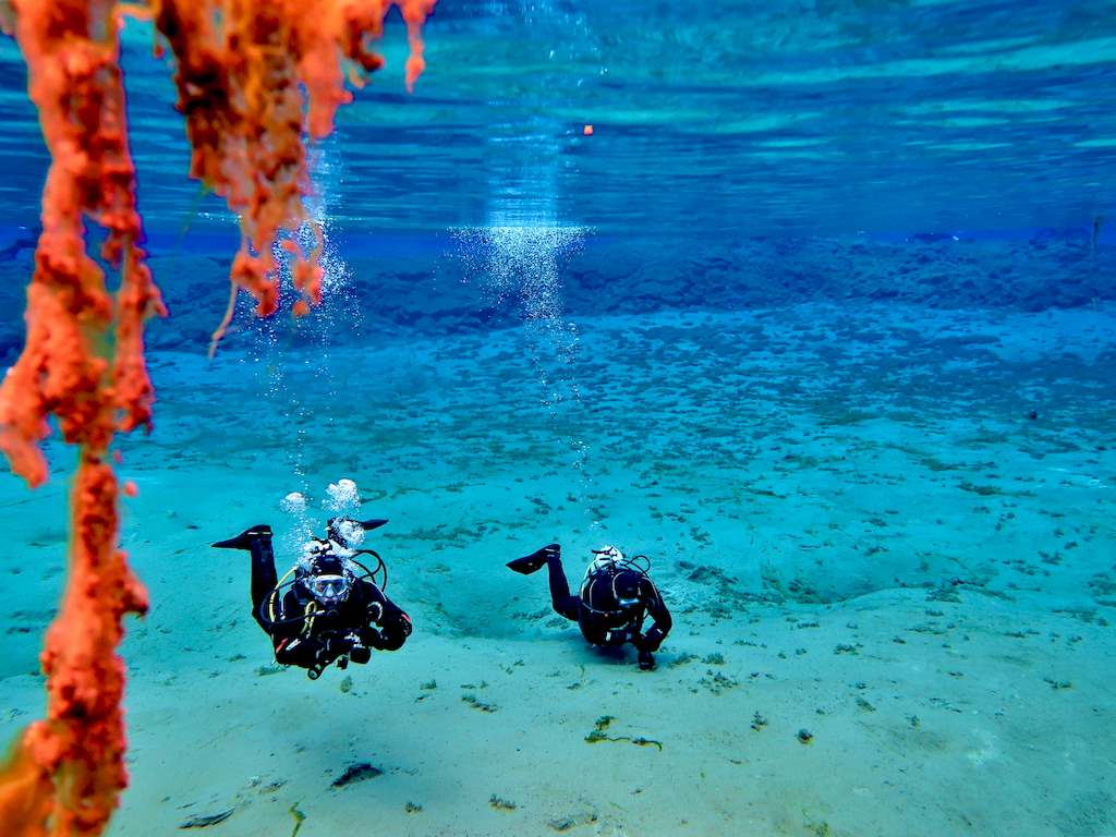 Deux plongeurs évoluent dans le lac à la sortie de la faille de Silfra