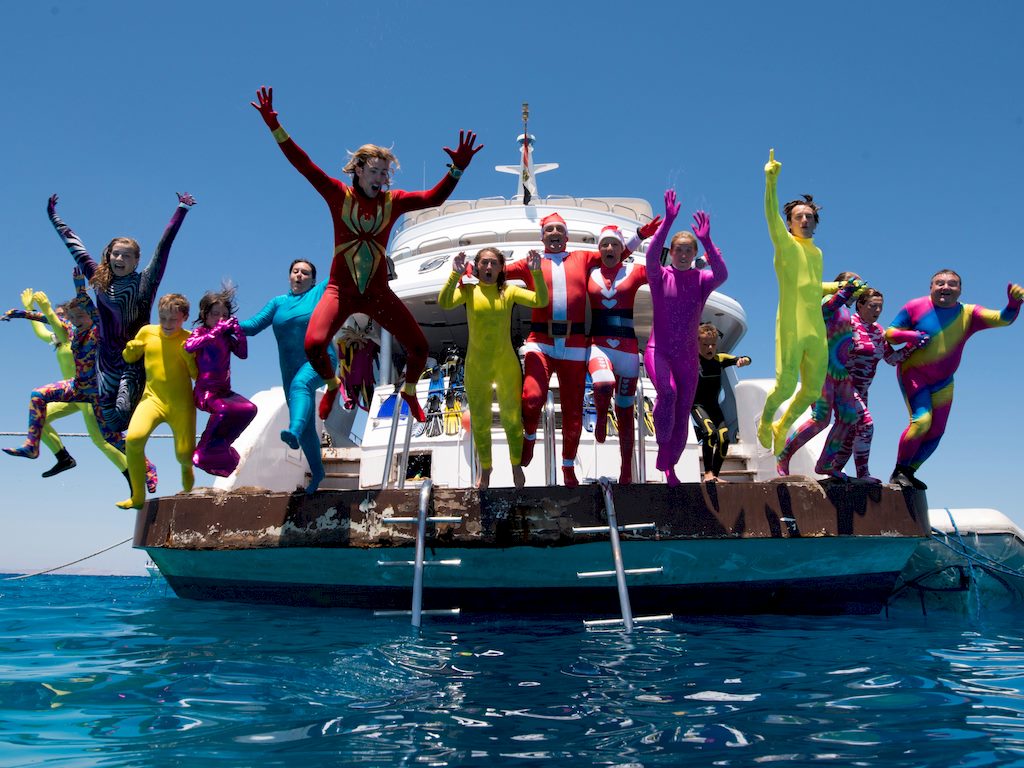 Des plongeurs en tenues multicolores sautent tous ensembles d'un bateau