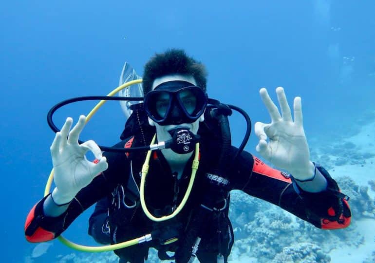 Check du matériel de plongée. Un plongeur fait le signe ok avec ses deux mains pour signifier qu'il l'a bien réalisé