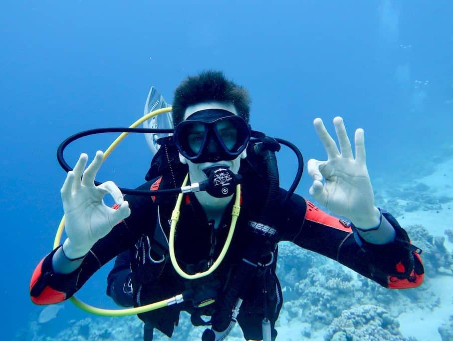 Check du matériel de plongée. Un plongeur fait le signe ok avec ses deux mains pour signifier qu'il l'a bien réalisé