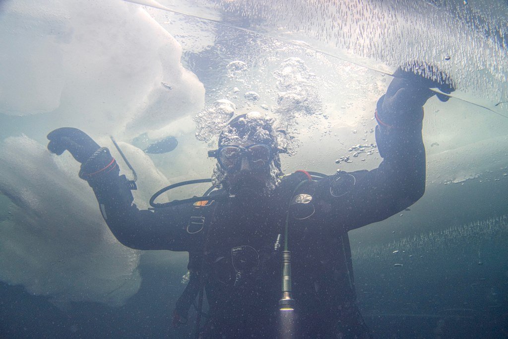 Un plongeur s'apprête à sortir de l'eau lors d'une plongée sous glace.