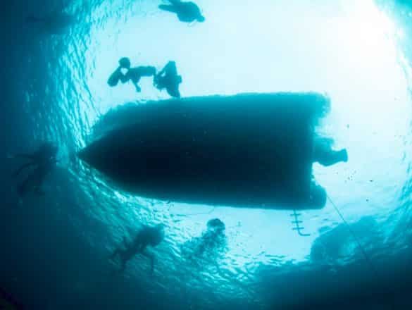Un bateau de plongée vu du dessous emmène des plongeurs pour une expéditions dans le climat de plongée et coronavirus.
