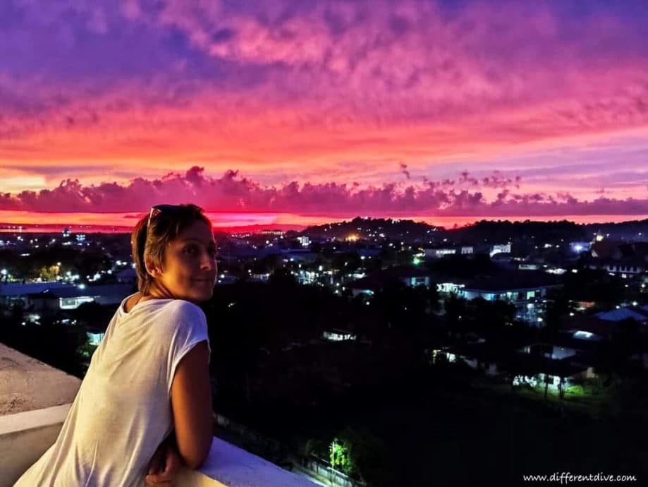 Hélène Adam sur une terrasse de Sorong devant un coucher de soleil.