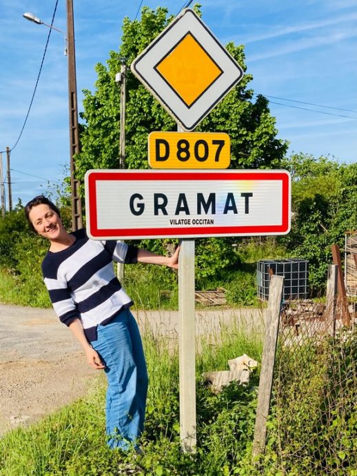 Hélène Adam devant le panneau d'entrée de la commune de Gramat.