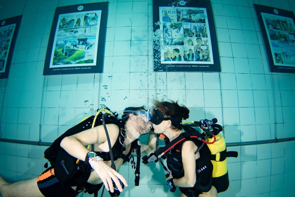 Des amoureux s'embrassent sous l'eau en plongée.