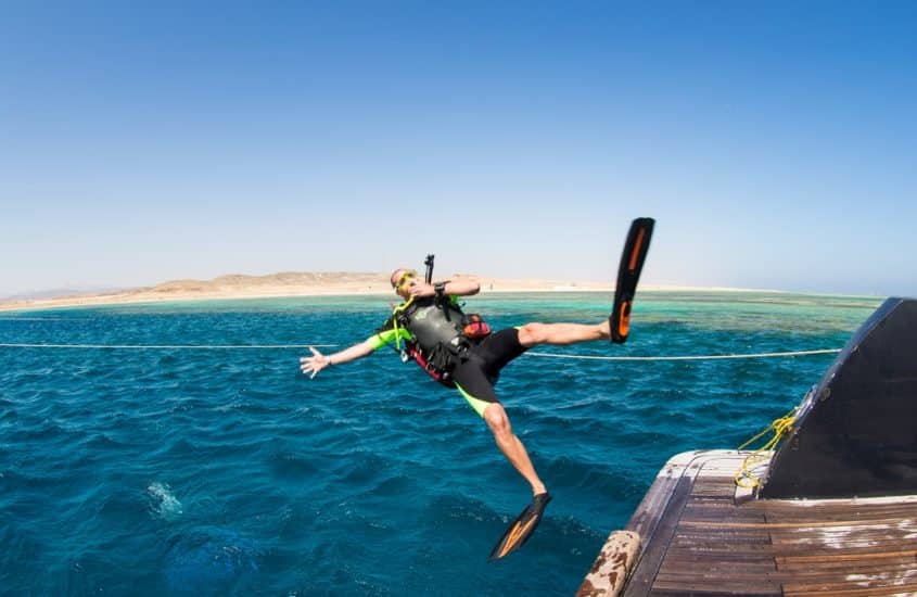 Un plongeur s'élance dans l'eau bras et jambes écartés pour faire un saut droit de plongée.
