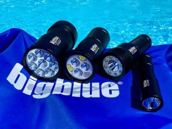 4 lampes de plongée Bigblue étalées au bord d'une piscine.