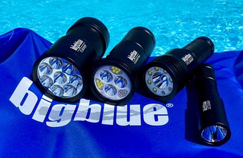 4 lampes de plongée Bigblue étalées au bord d'une piscine.