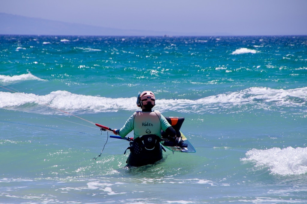Un rider entre dans l'eau avec sa planche de kitesurf à Tarifa.