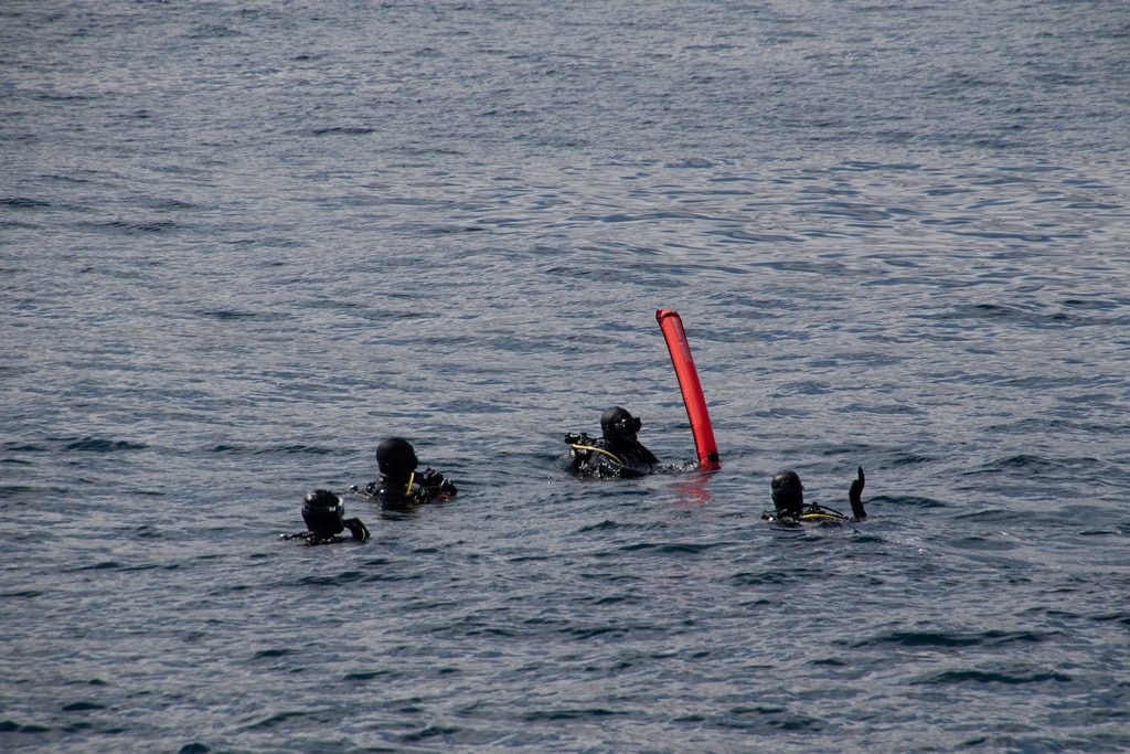 Quatre plongeurs en mer avec un parachute.