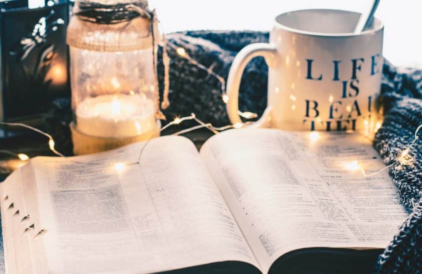 Une tasse et une lumière derrière un livre pour illustrer les livres qui changent la vie professionnelle.