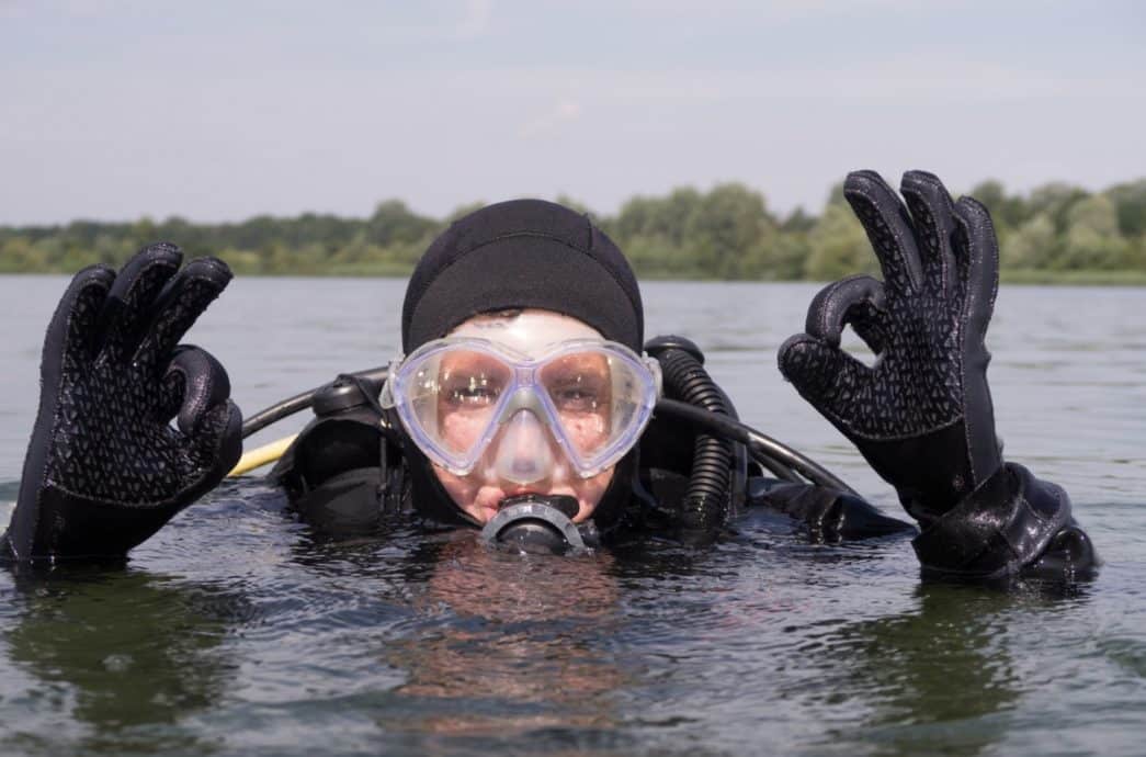 Un jeune fait le signe OK avec ses deux mains en étant en surface avant de plonger.
