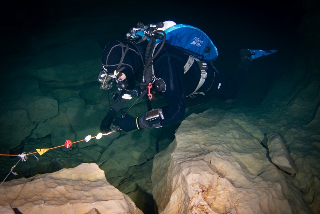 Un plongeur pose un cookie sur une ligne de vie en plongée souterraine dans le Lot